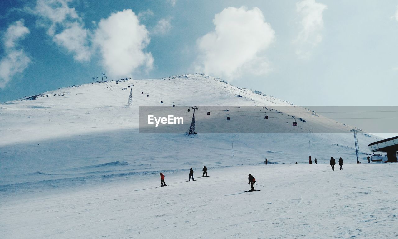 People skiing on snowcapped mountain against sky