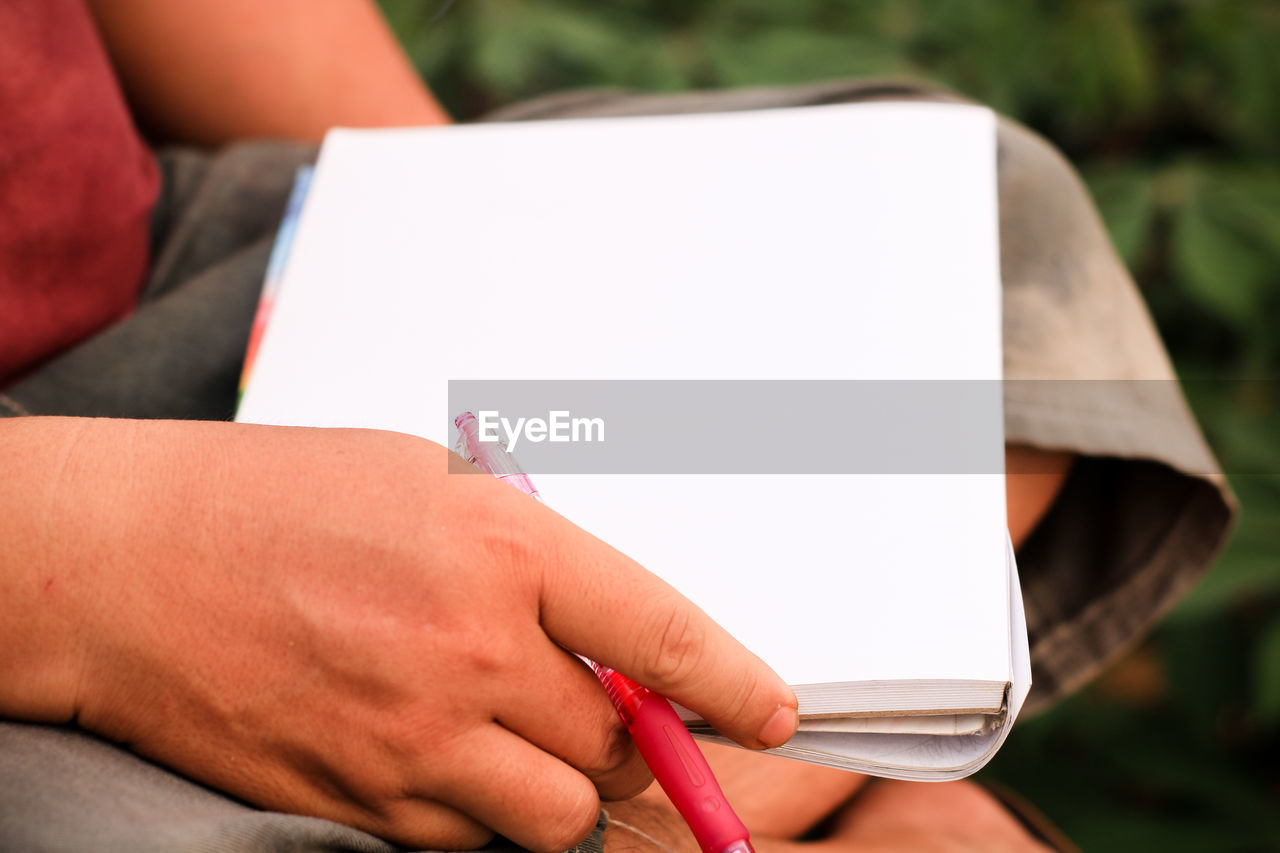 Cropped hand of person holding blank paper in city