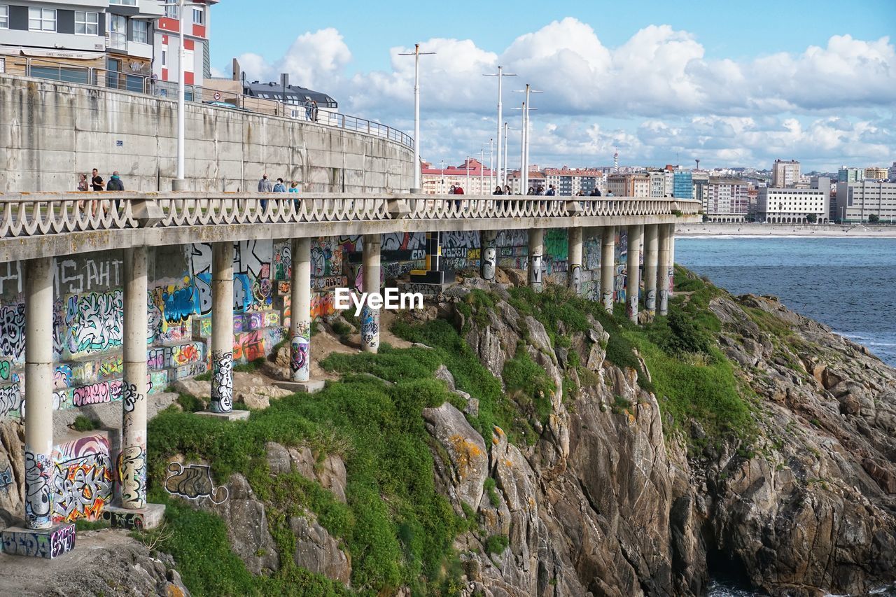 Bridge over sea amidst buildings in city against sky