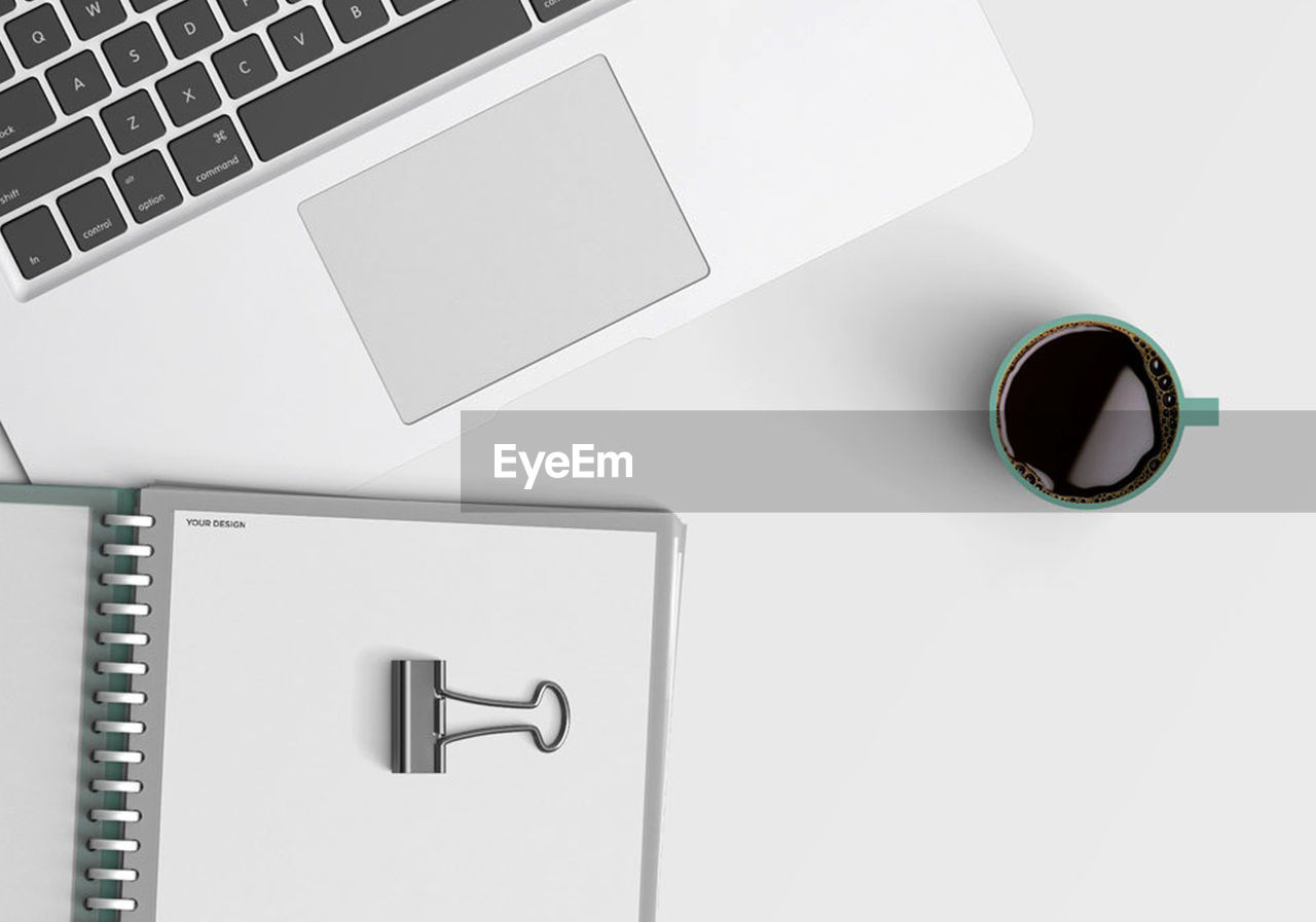 Directly above shot of laptop with diary and coffee cup on gray background