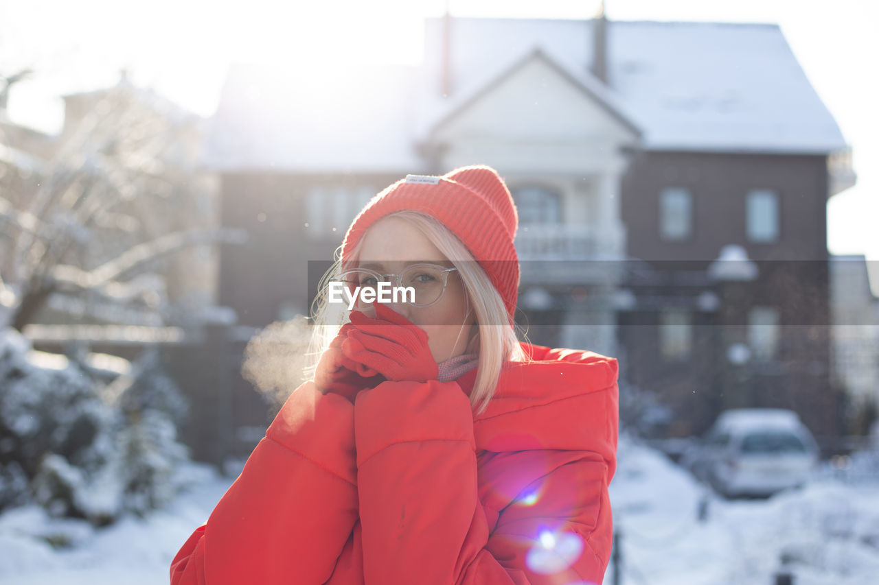 Young stylish blonde woman on the street has fun, posing in snowy, frosty