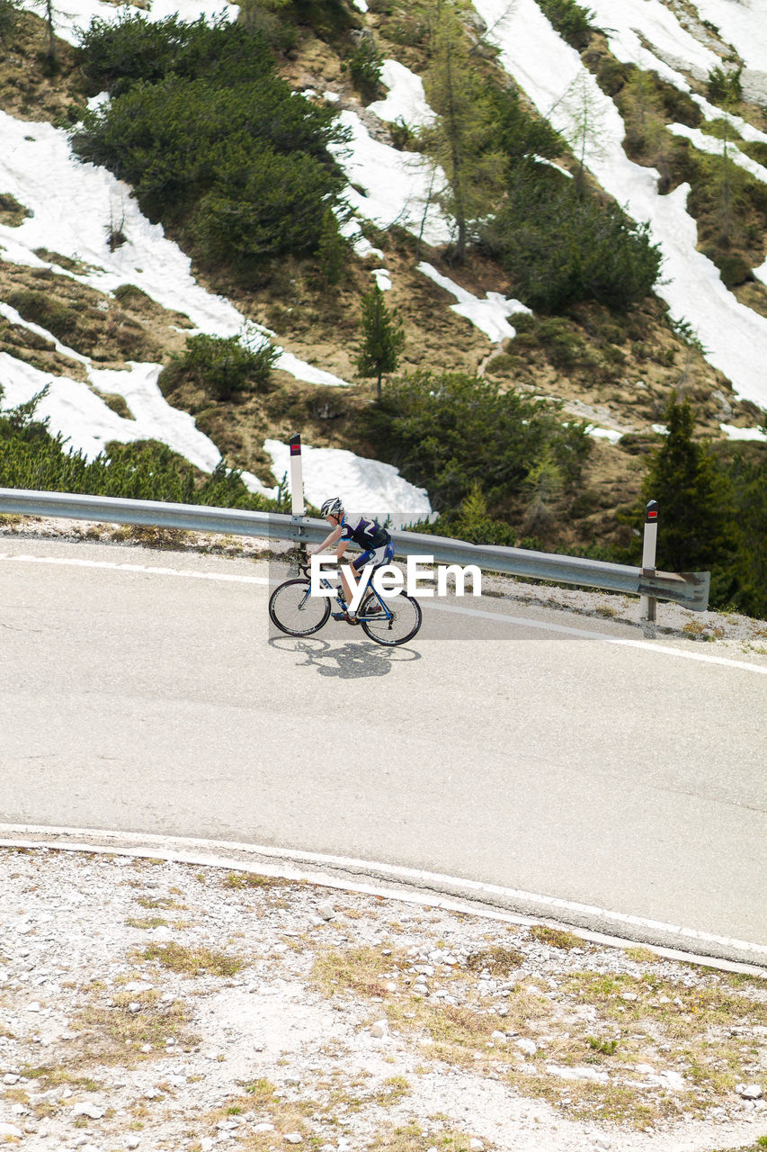 Woman riding bicycle on road by snowy mountain