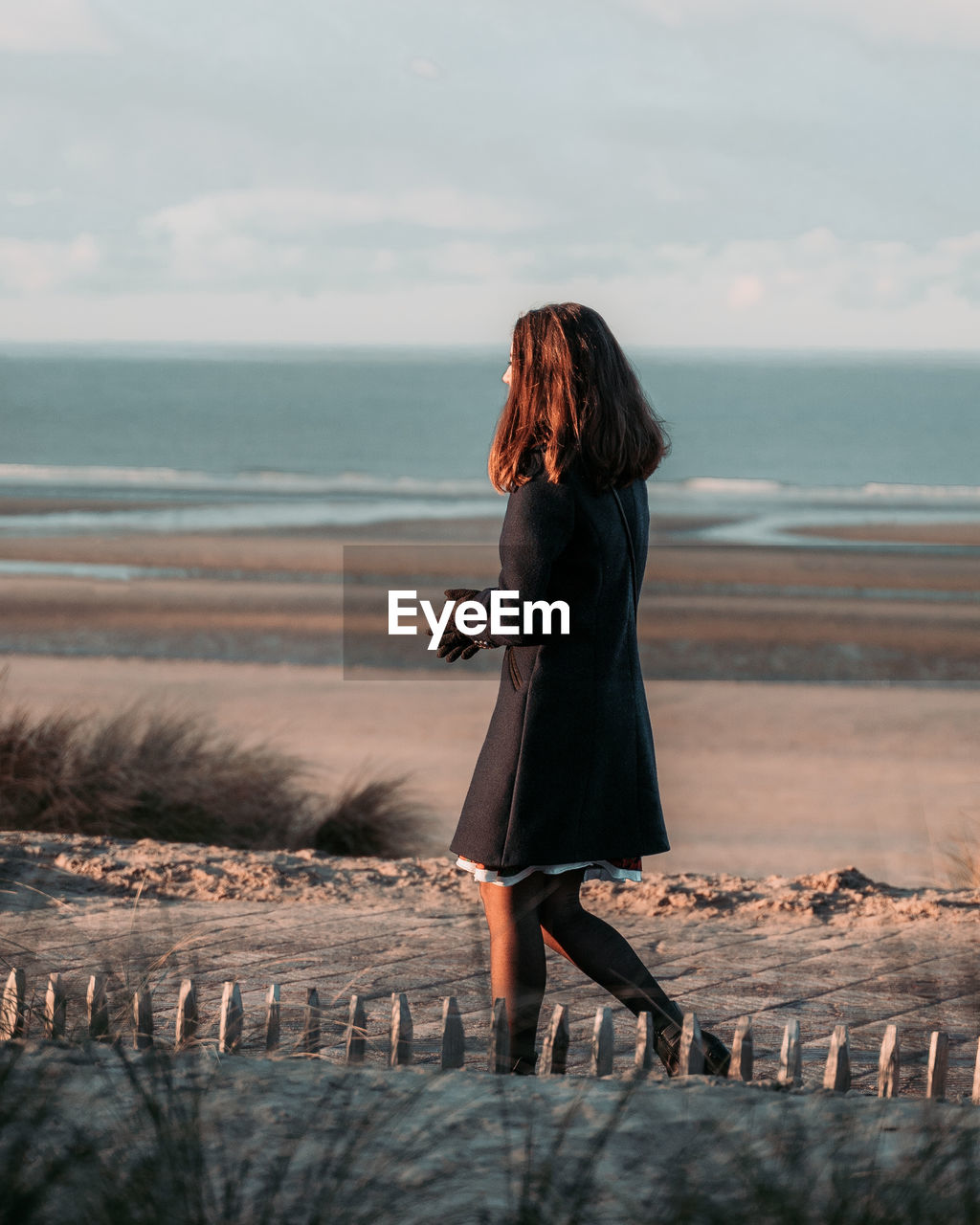 Side view of woman walking at beach against sky