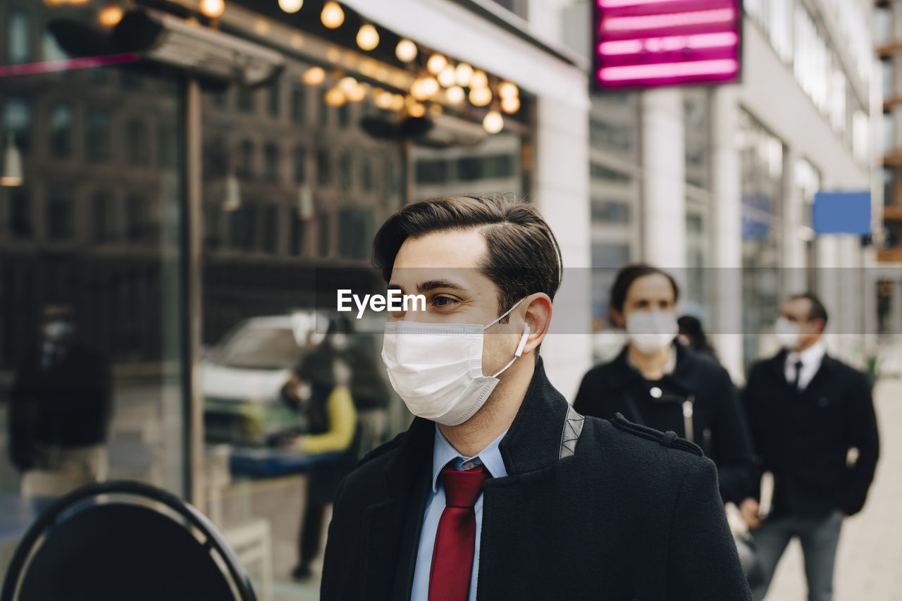 Business people standing in line outside store during pandemic