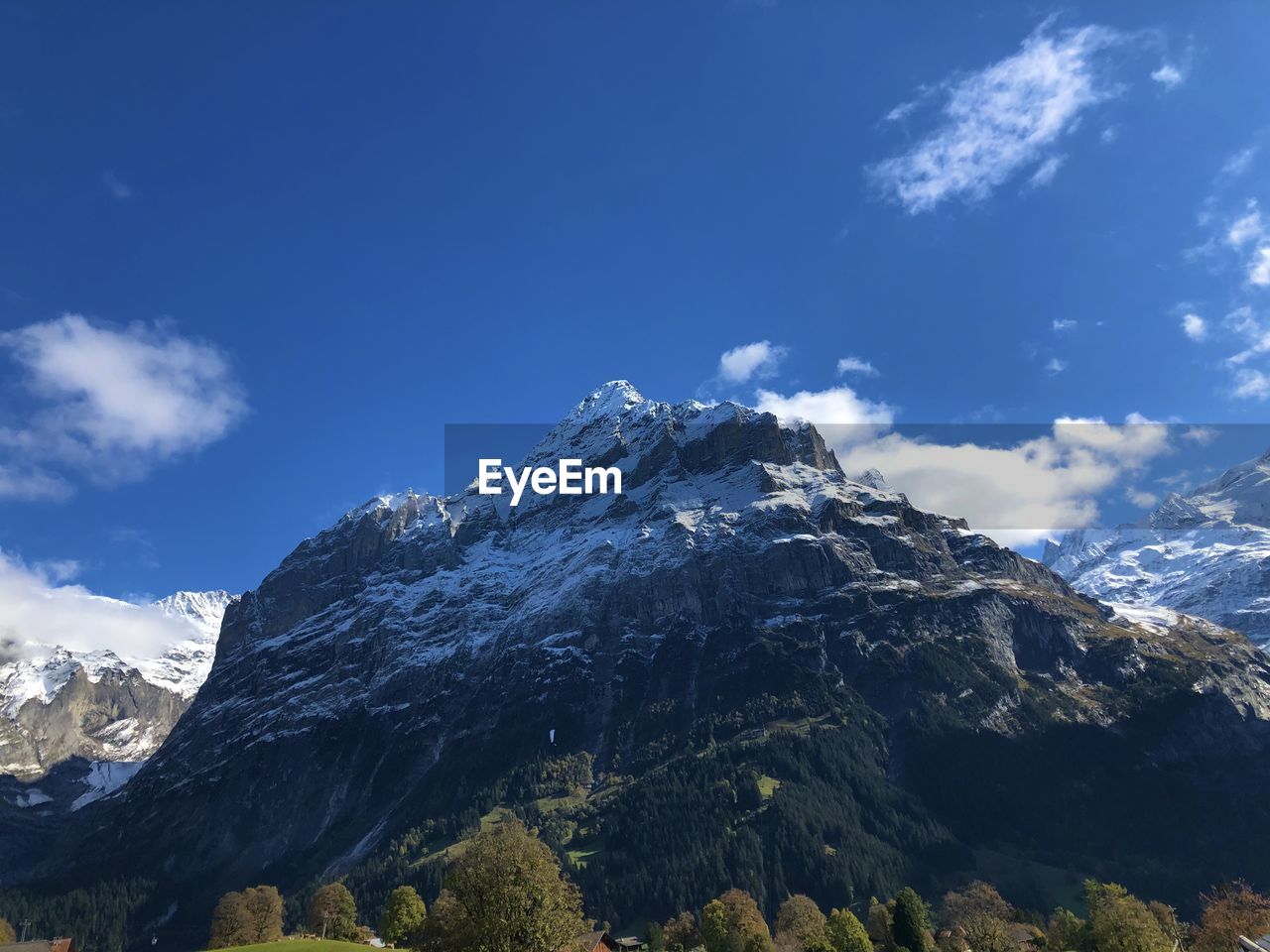 Low angle view of snowcapped mountains against blue sky