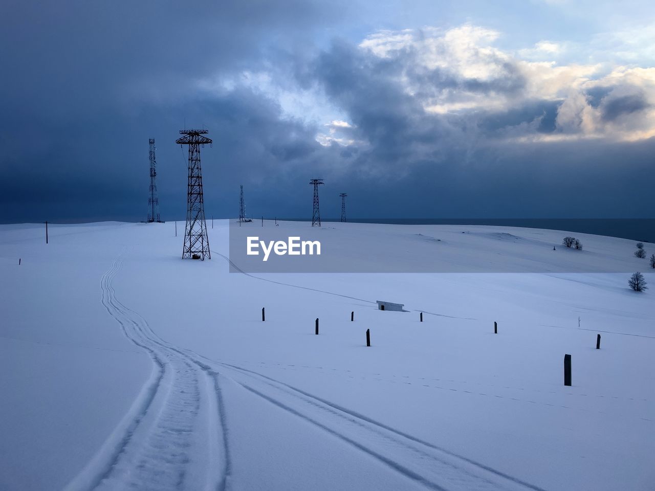 Transmission towers in the mountains during winter on a cloudy day