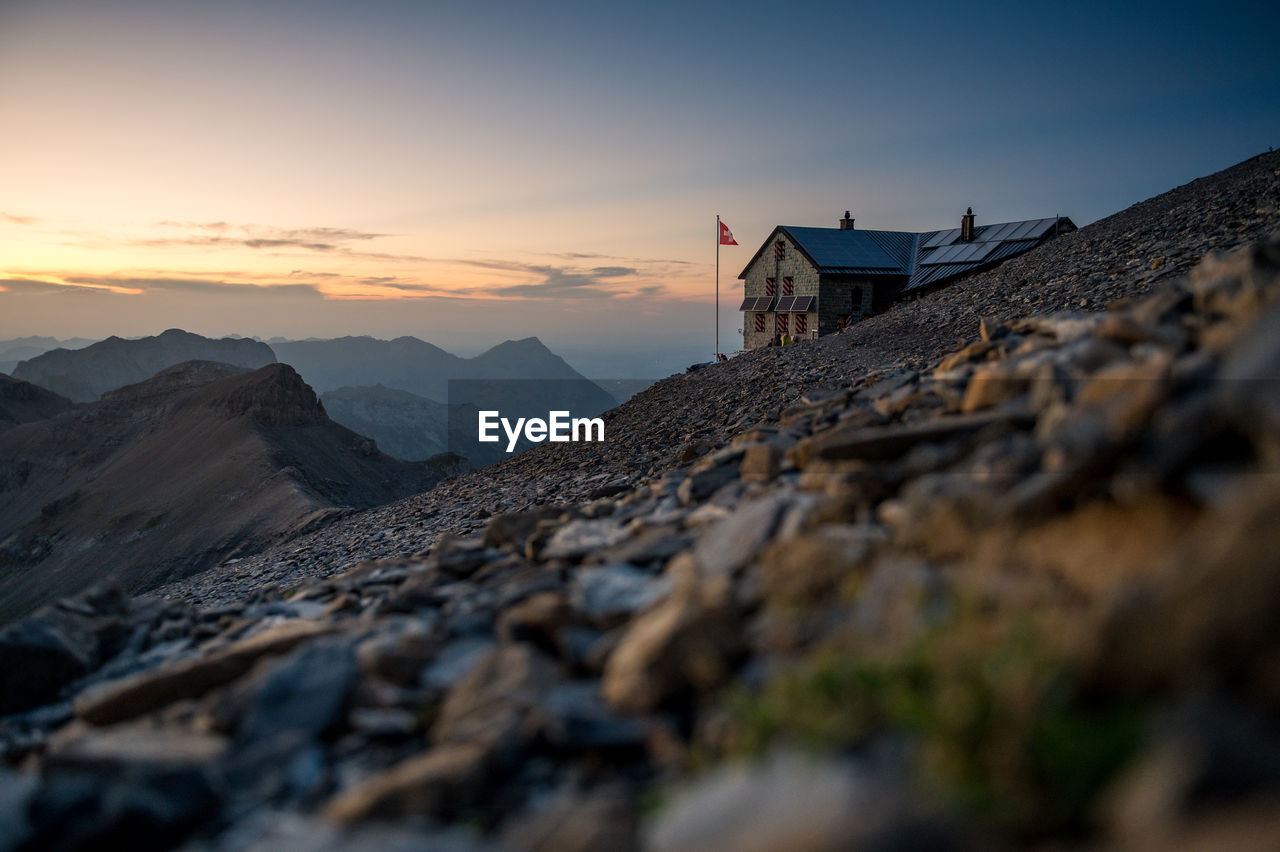 Surface level of land against house and sky during sunset