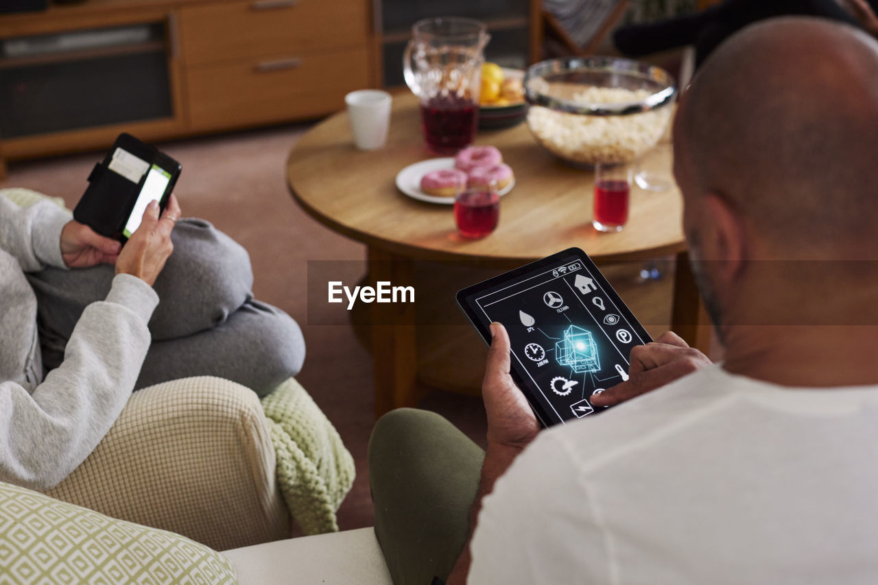 Family relaxing in living room and using phone and tablet