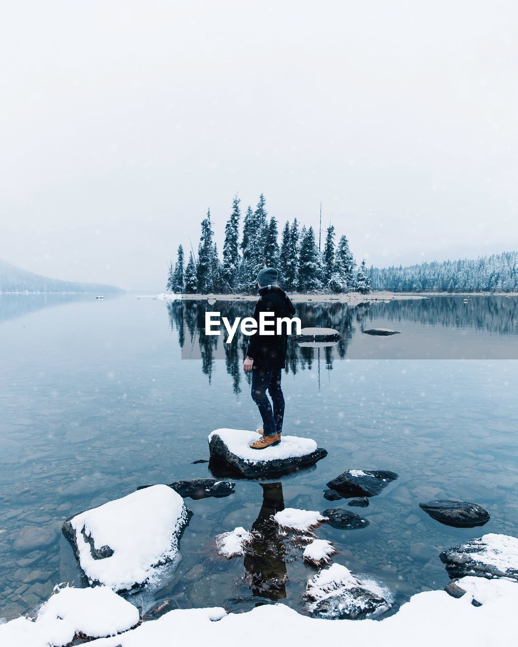 FULL LENGTH REAR VIEW OF MAN STANDING ON FROZEN LAKE