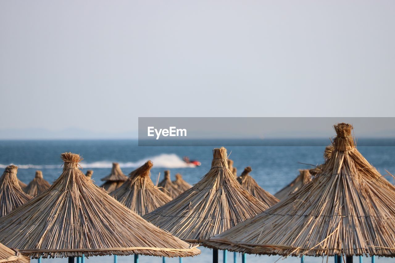 Thatched roofs at beach against clear sky