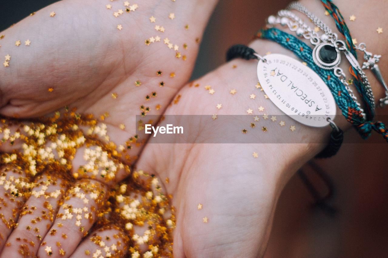 Cropped hands of woman holding golden star shape glitters