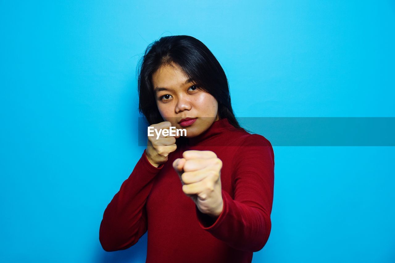 PORTRAIT OF TEENAGE GIRL HOLDING BLUE BACKGROUND