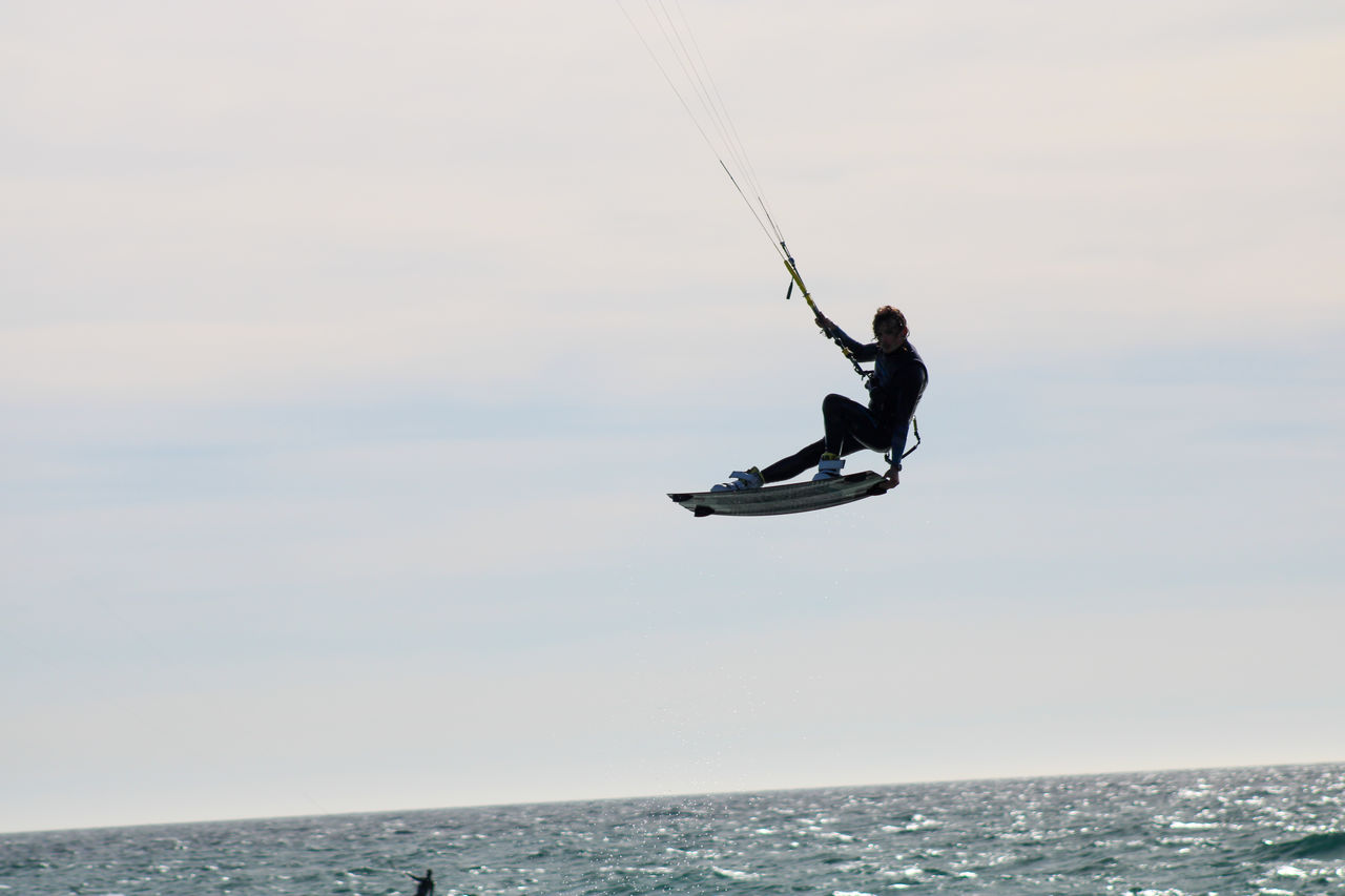 Man jumpinh surfing in sea against sky