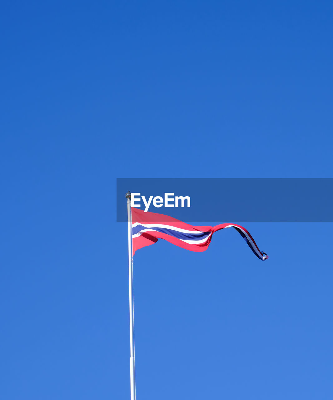 Low angle view of flag against clear blue sky