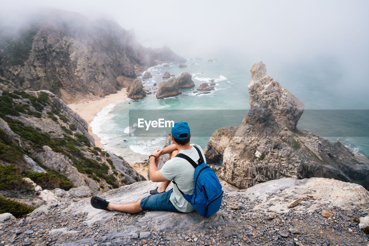 High angle view of man sitting on rock against sea