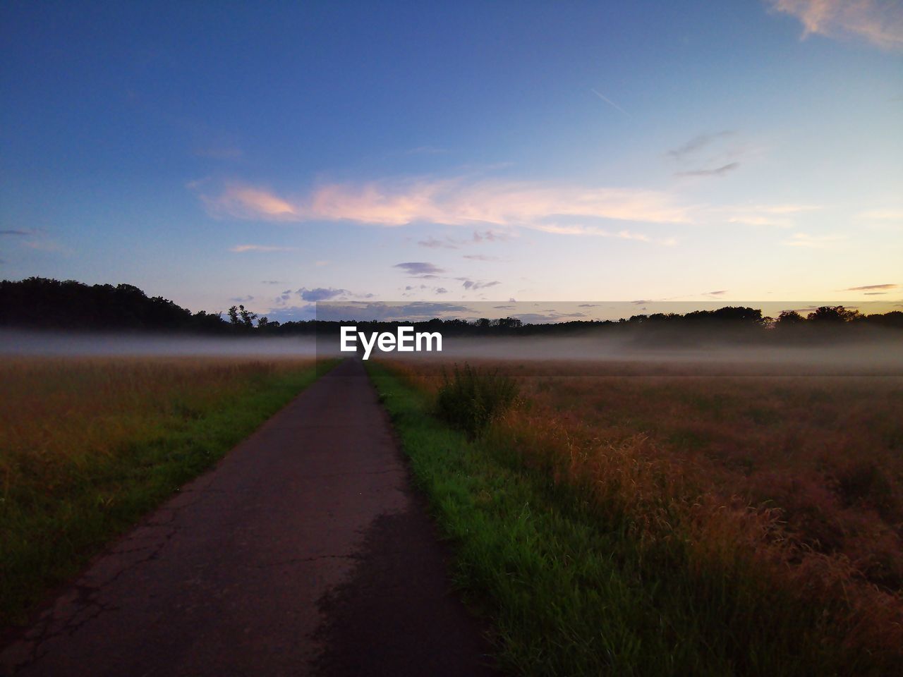 DIRT ROAD AMIDST FIELD AGAINST SKY