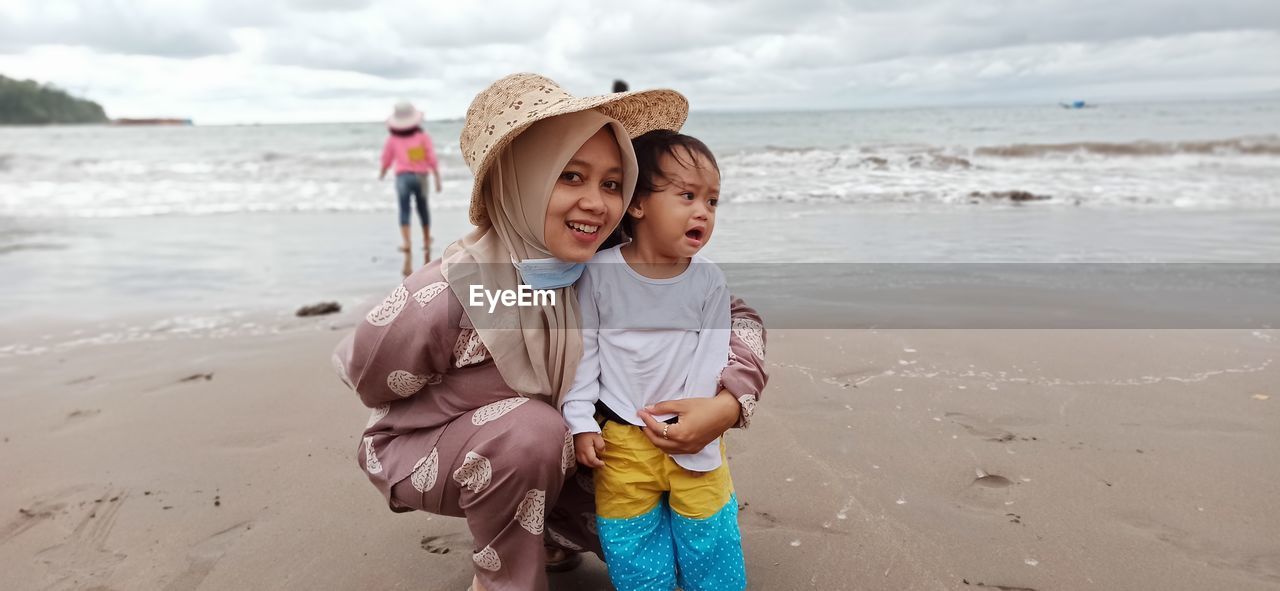 Portrait of smiling mother with crying daughter at beach