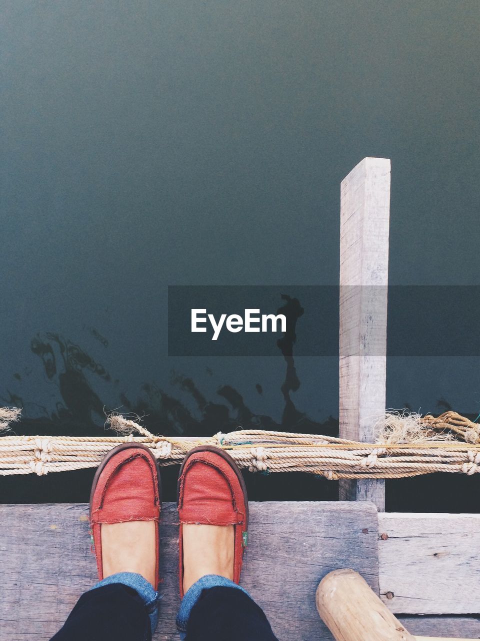 Low section of woman wearing shoes standing on pier