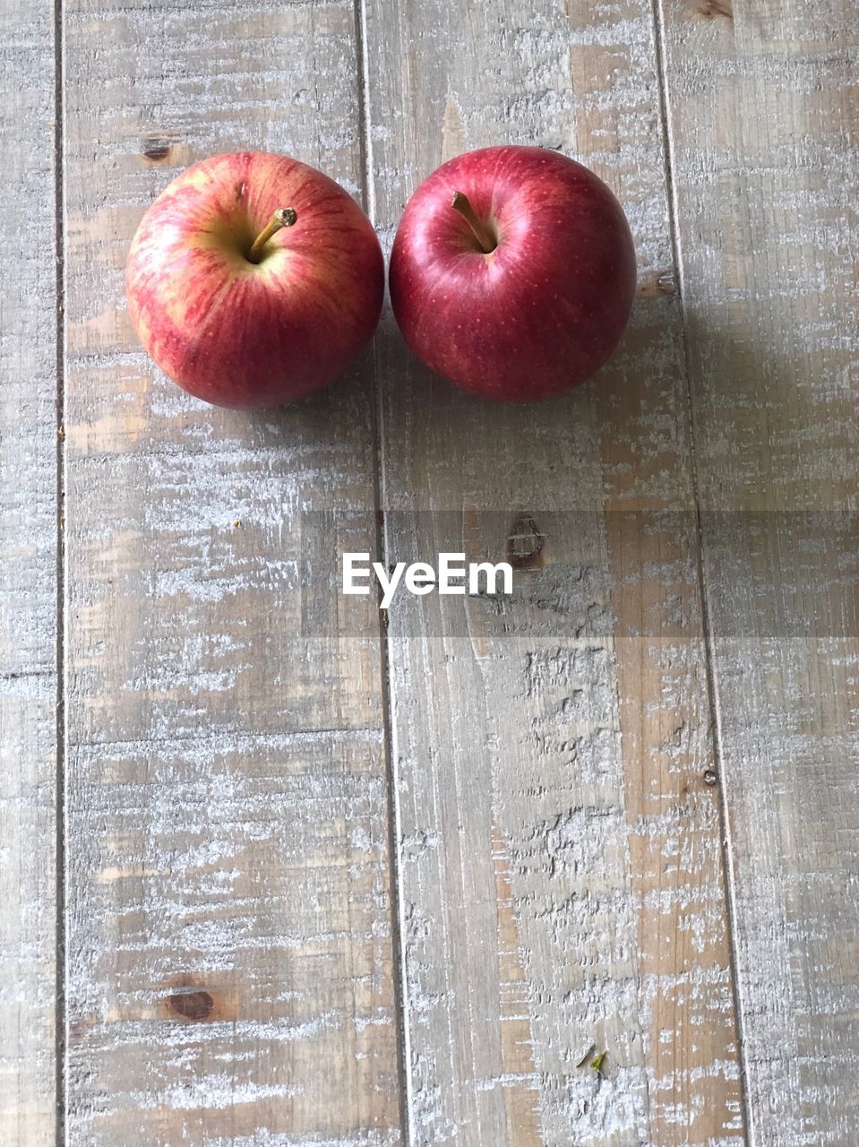 HIGH ANGLE VIEW OF APPLES ON TABLE AGAINST WALL