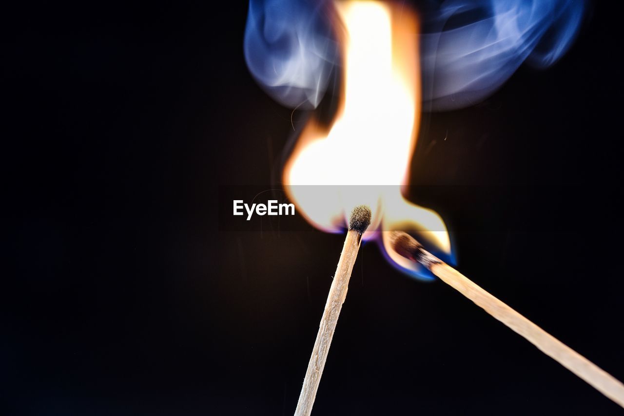 Close-up of burning matchsticks against black background
