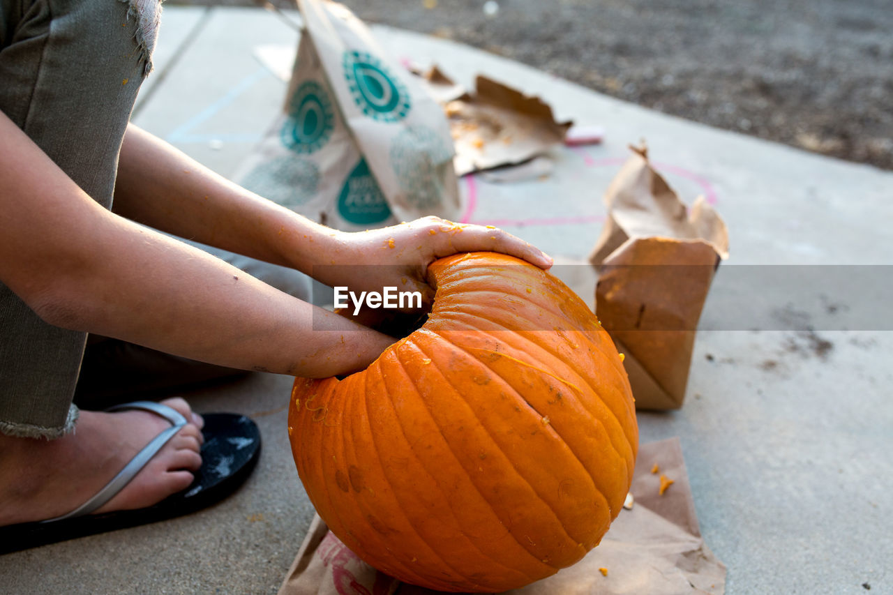 Girl reaches into pumpkin during the carving process