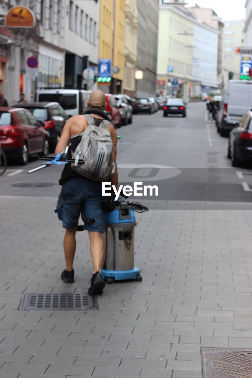 REAR VIEW OF WOMAN WALKING ON STREET