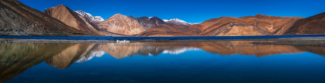 Reflection of mountain range in lake against clear blue sky