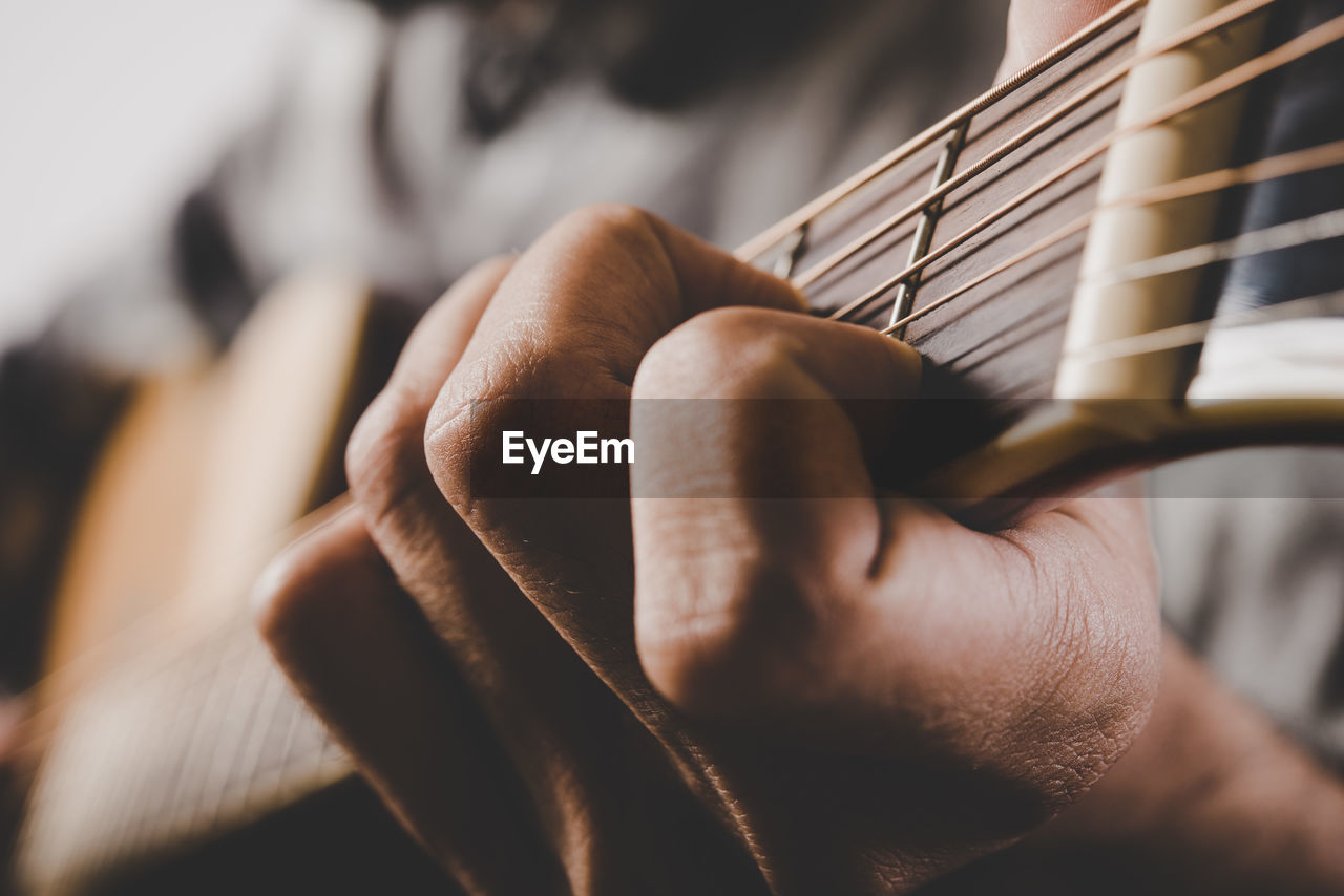 CLOSE-UP OF HAND HOLDING GUITAR