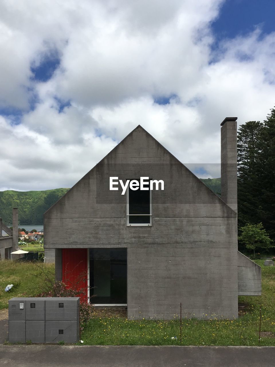 HOUSE ON FIELD BY BUILDINGS AGAINST SKY