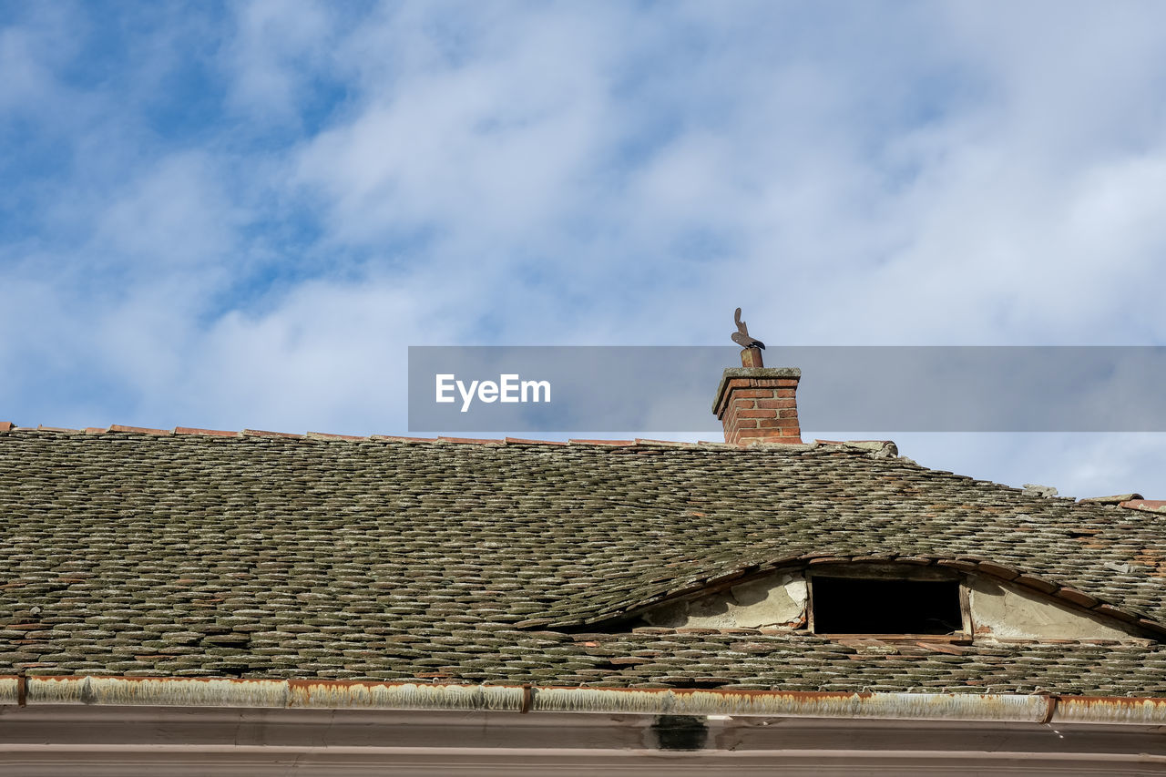 Romanian ceramic shingle roof with brick chimney and old television antenna