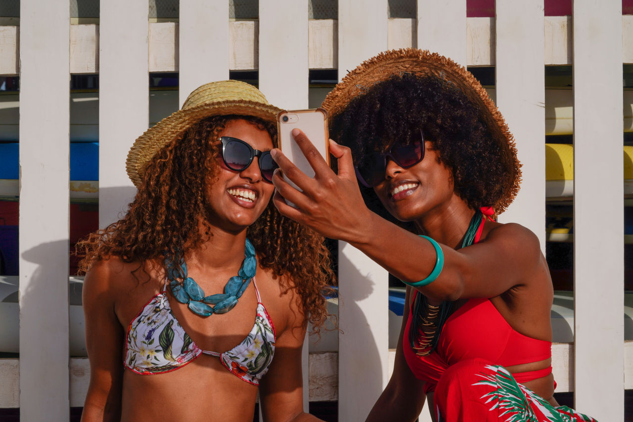 Two young black women taking selfie at the beach