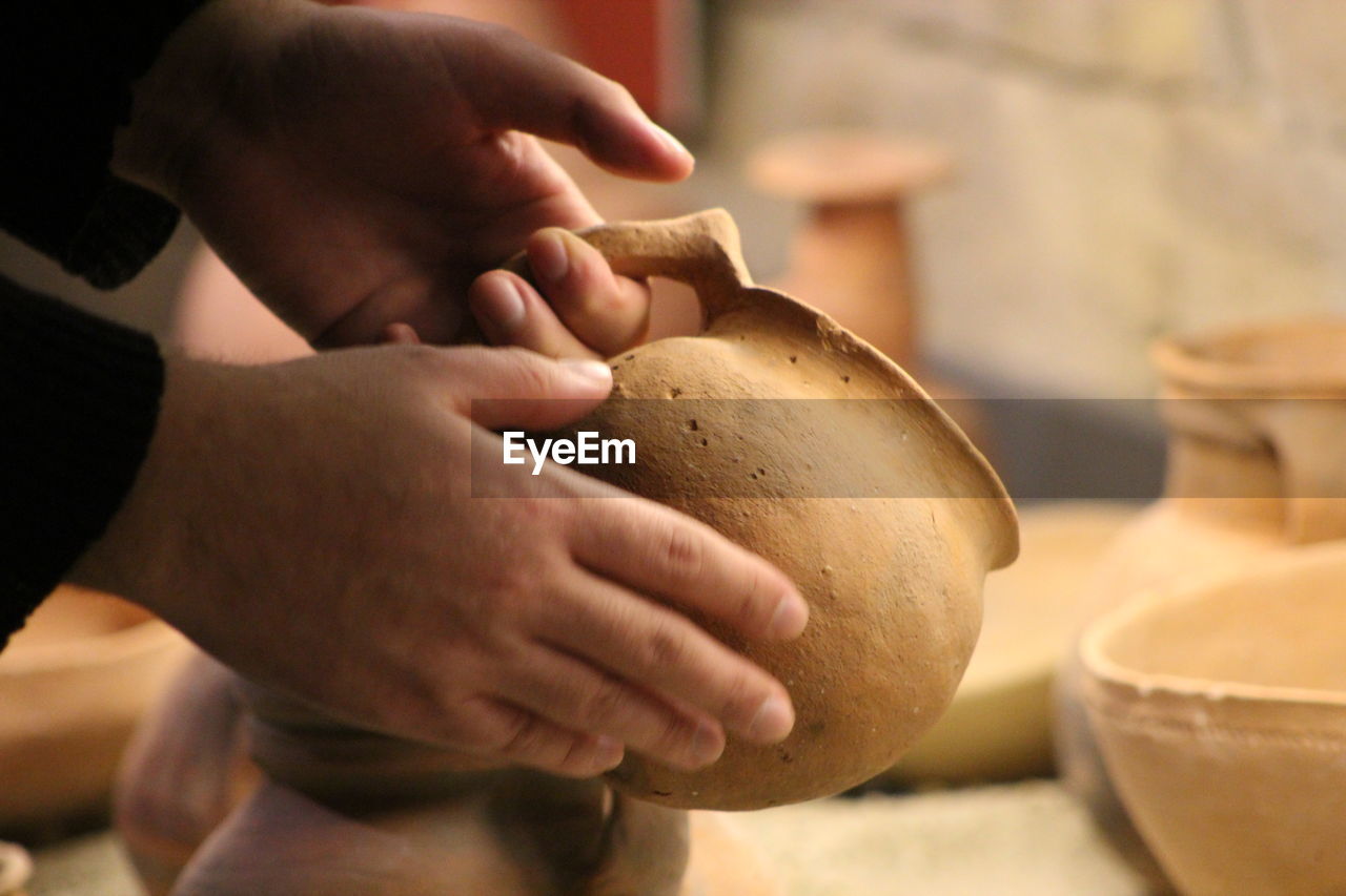 Cropped hands of man holding earthen pot