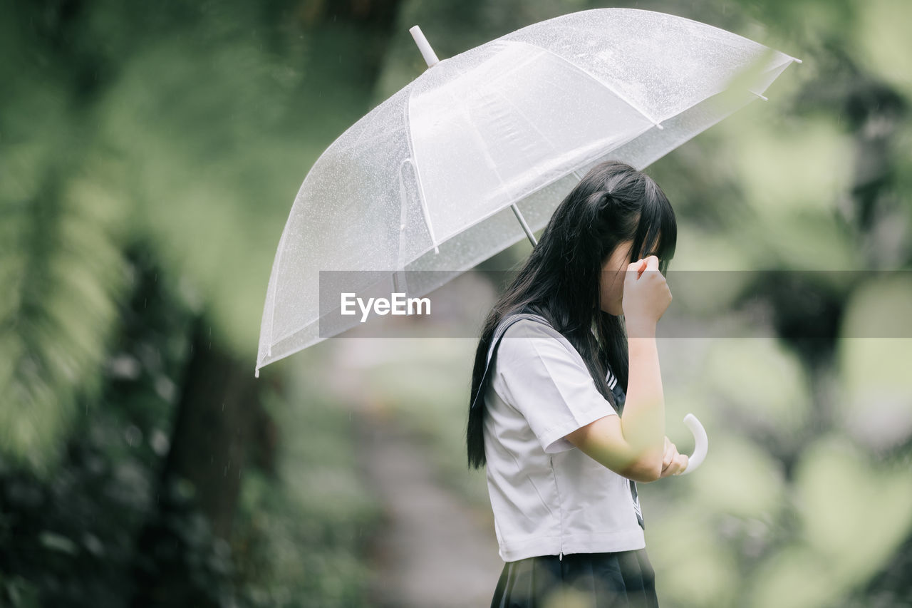 Woman with umbrella standing on wet rainy day