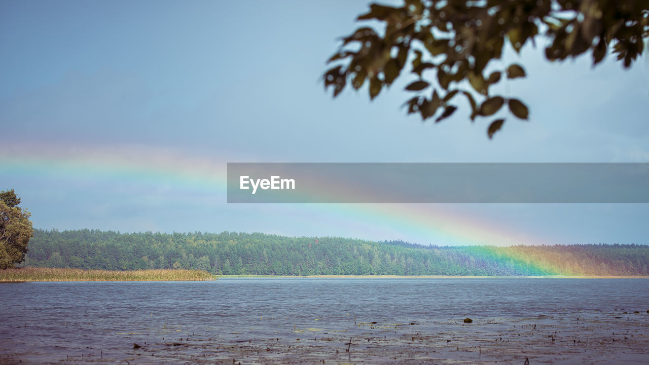 Scenic view of rainbow over lake against sky