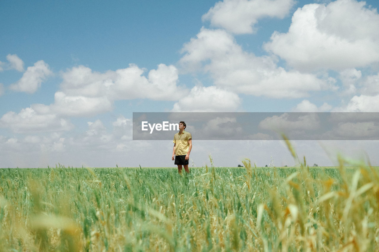 Man in open field with clouds. 