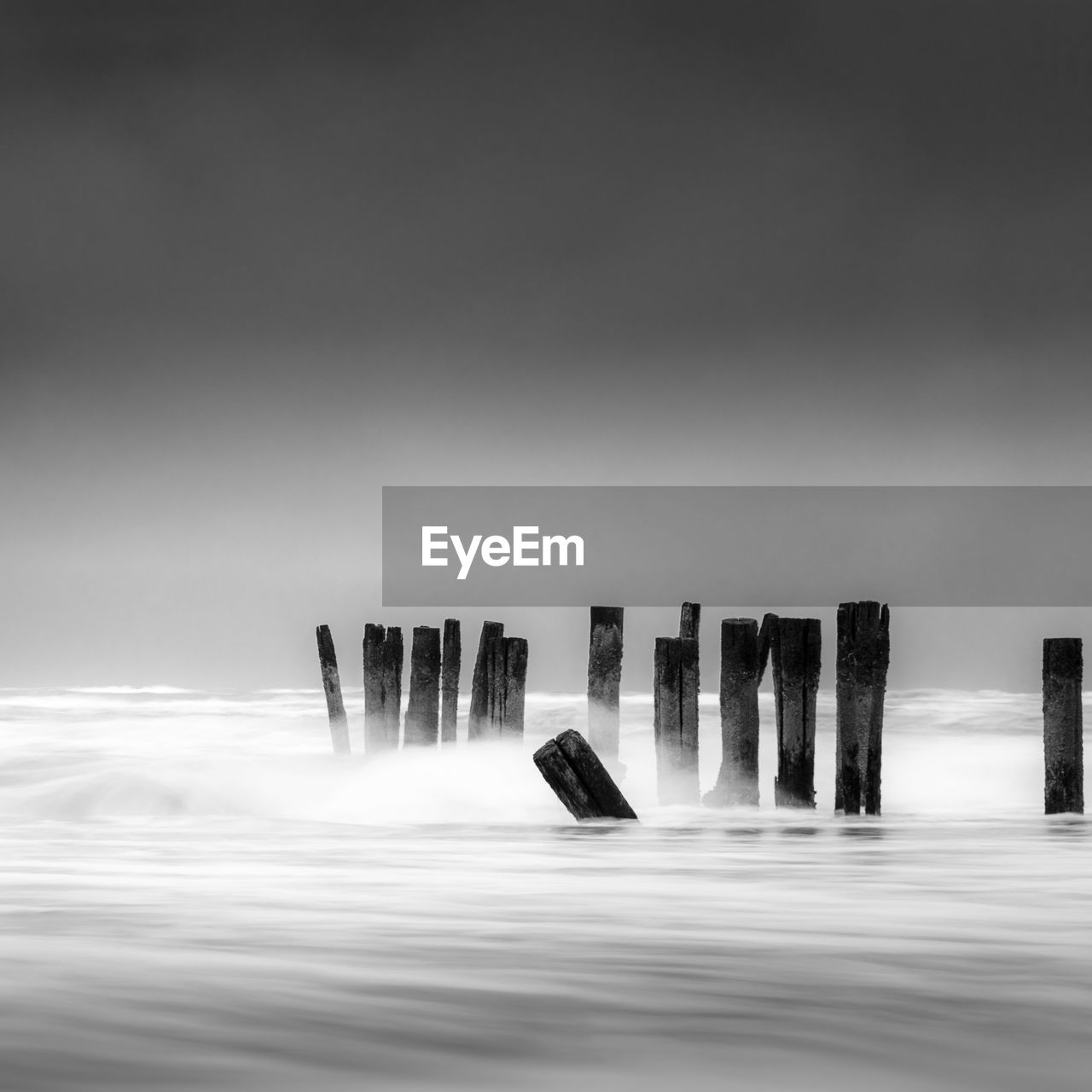 Wooden posts in sea against sky