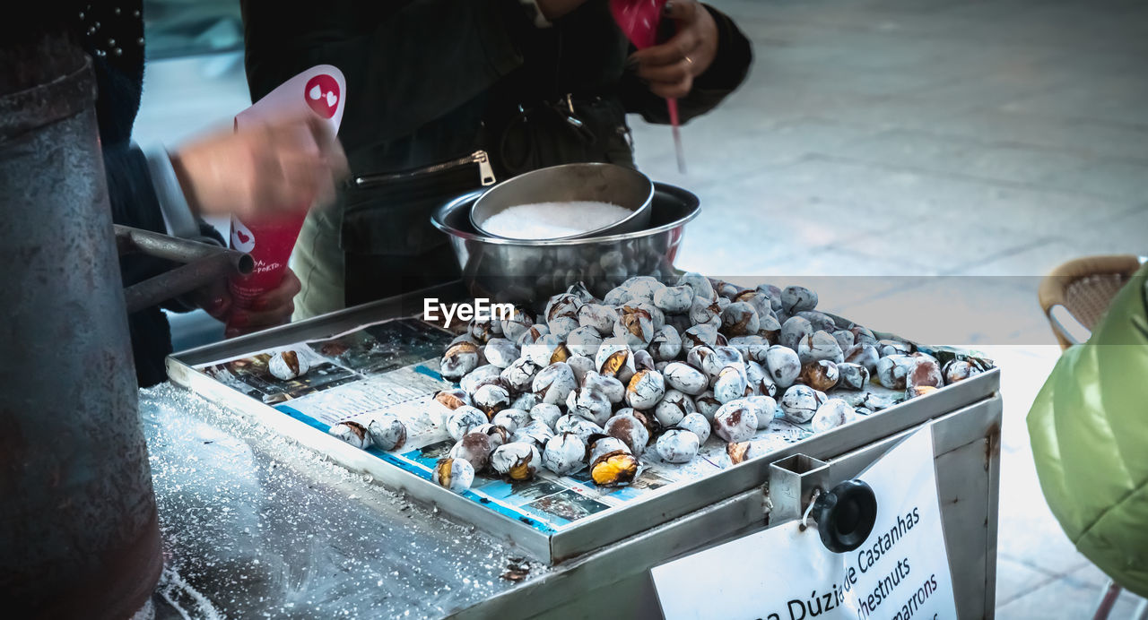 MIDSECTION OF MAN PREPARING FOOD AT MARKET STALL