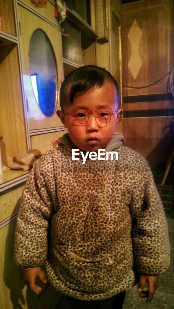 Portrait of boy wearing eyeglasses standing at home