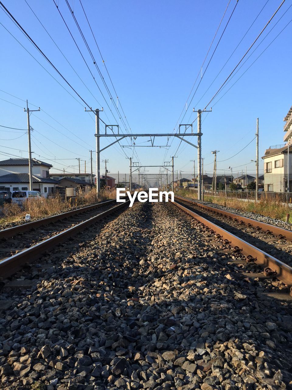 Surface level of railway tracks against clear blue sky