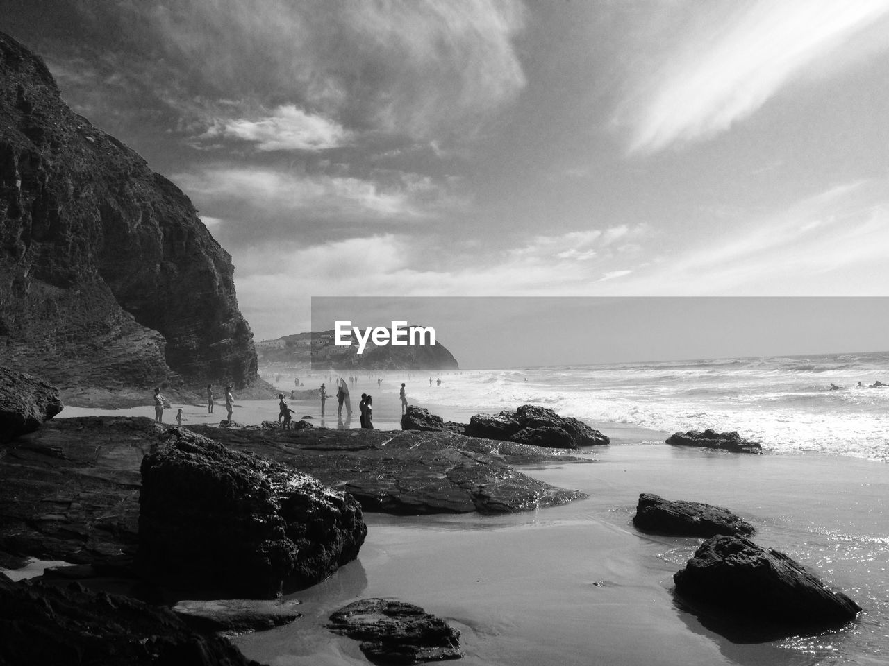 People on rocky beach against sky