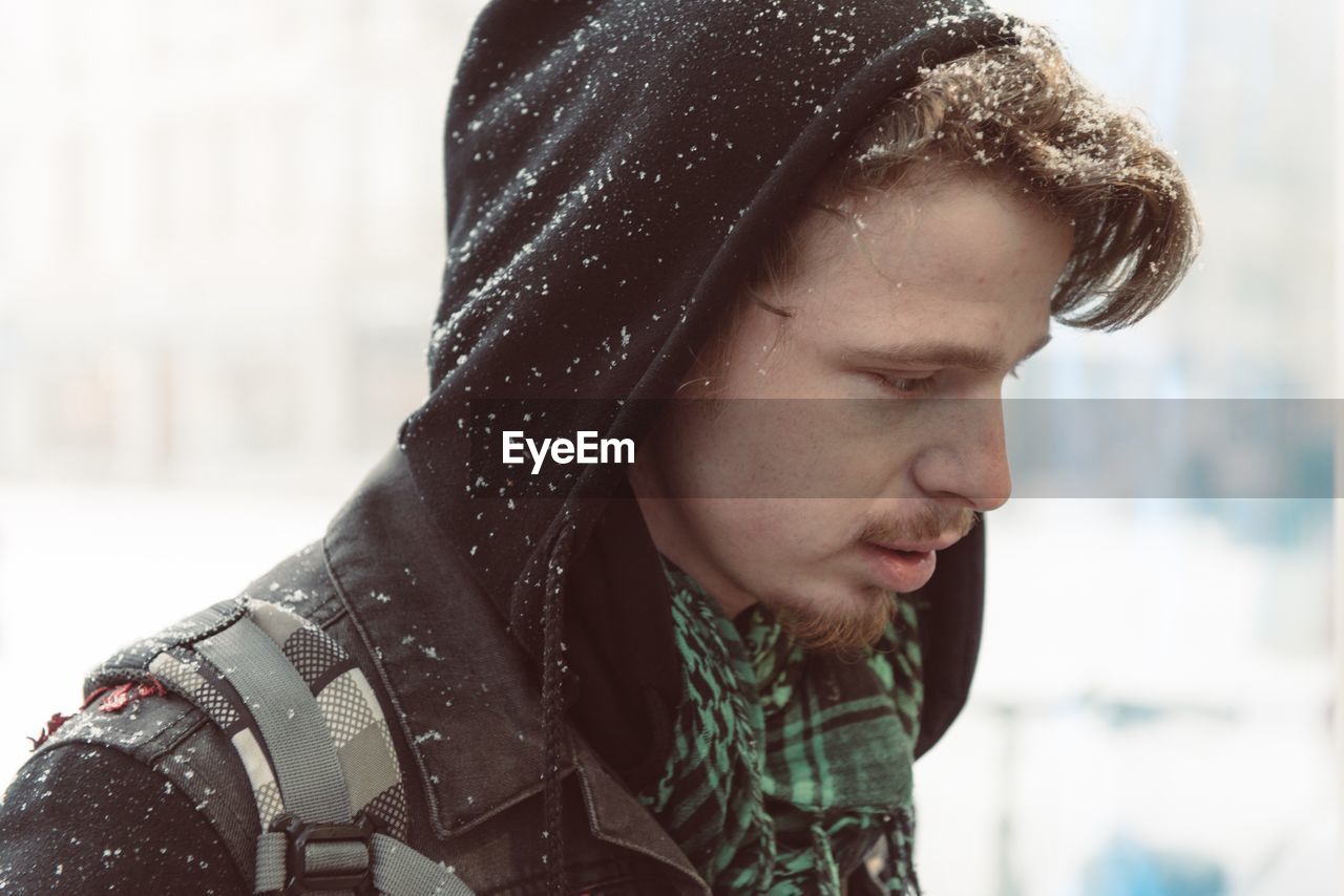 Close-up side view of young woman with snow on hood