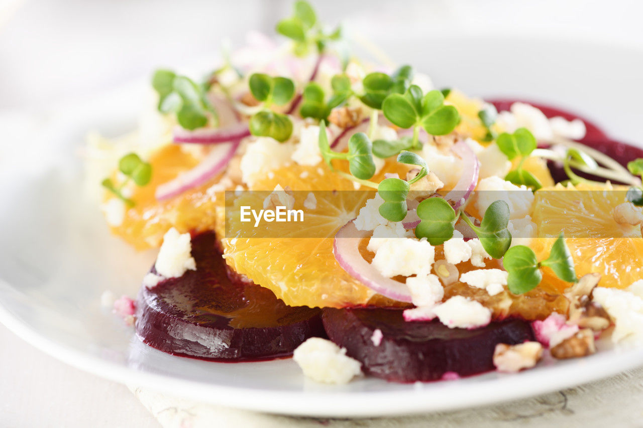 Orange salad with baked beetroot, goat cheese, microgreens and nuts.