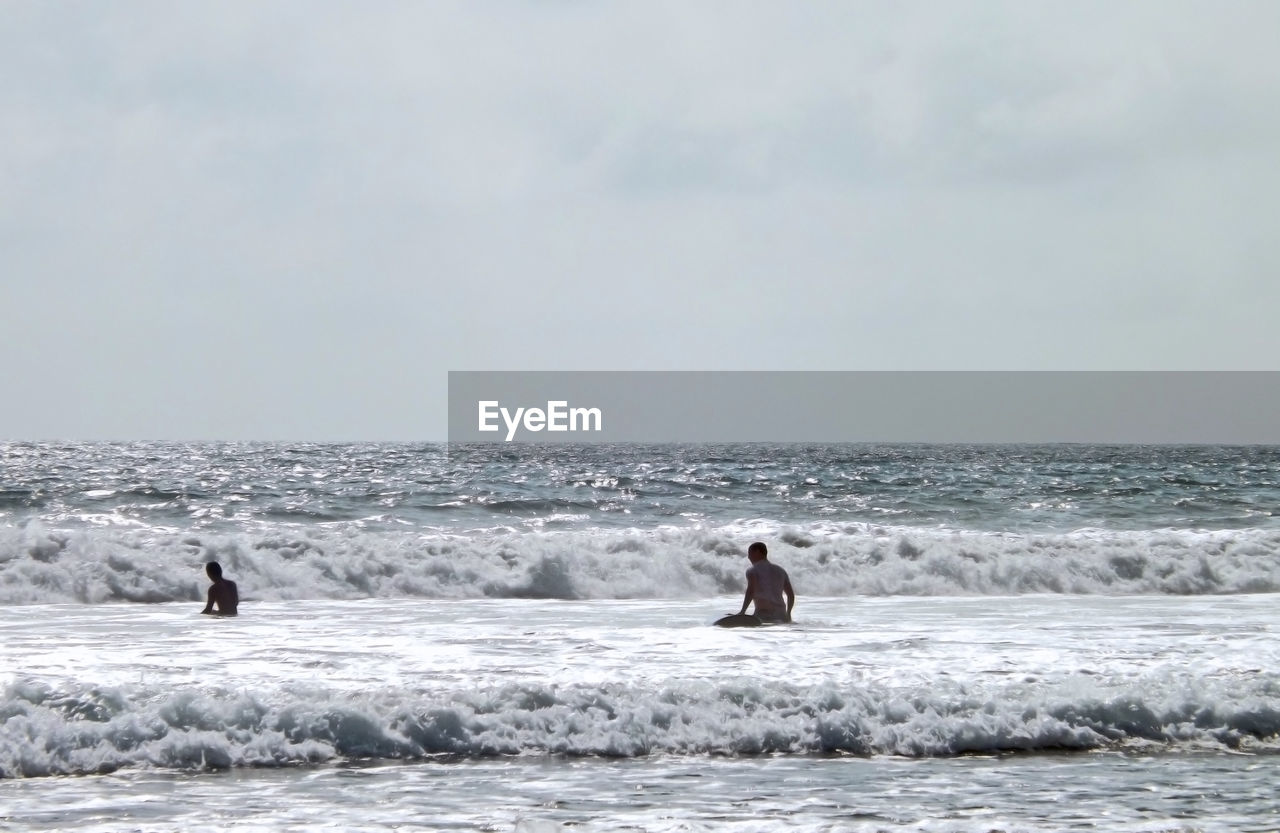 Men on beach against sky