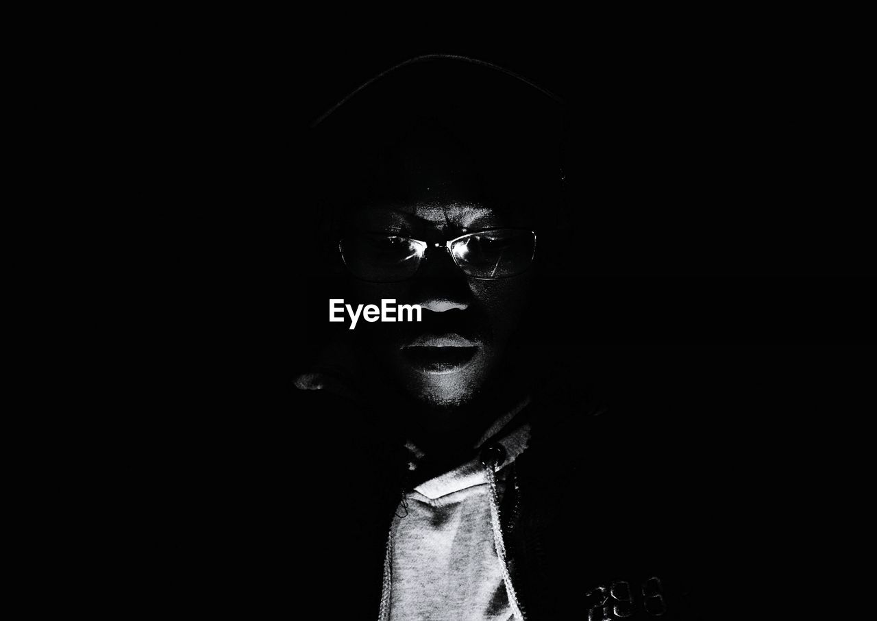 Young man wearing eyeglasses against black background