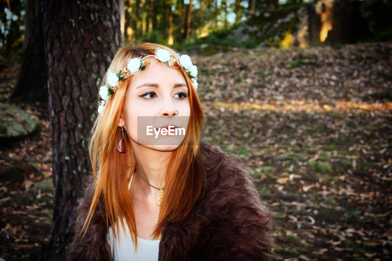 Beautiful young woman looking away in forest