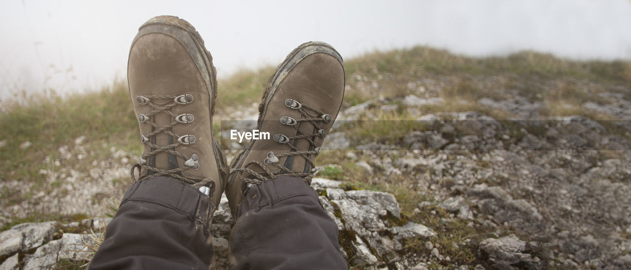 shoe, one person, low section, human leg, footwear, personal perspective, nature, grass, leisure activity, lifestyles, winter, limb, day, human limb, human foot, plant, adult, outdoors, relaxation, land, boot, hiking, standing, spring, casual clothing, sky, men, walking shoe