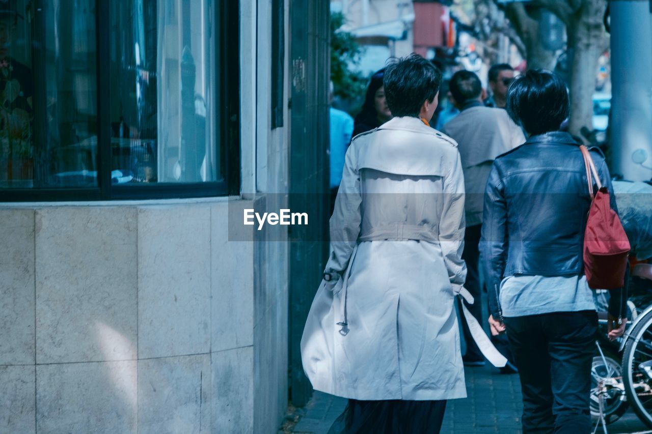 Rear view of female friends walking on sidewalk