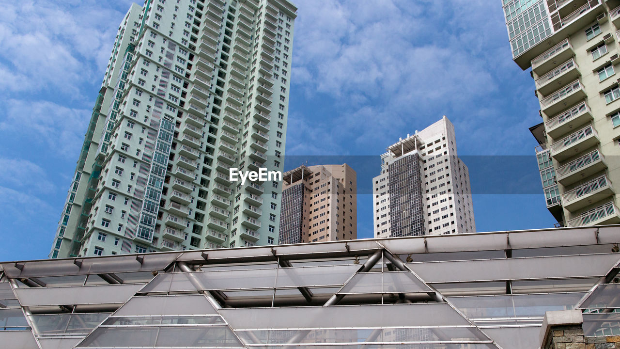 Low angle view of modern building against cloudy sky