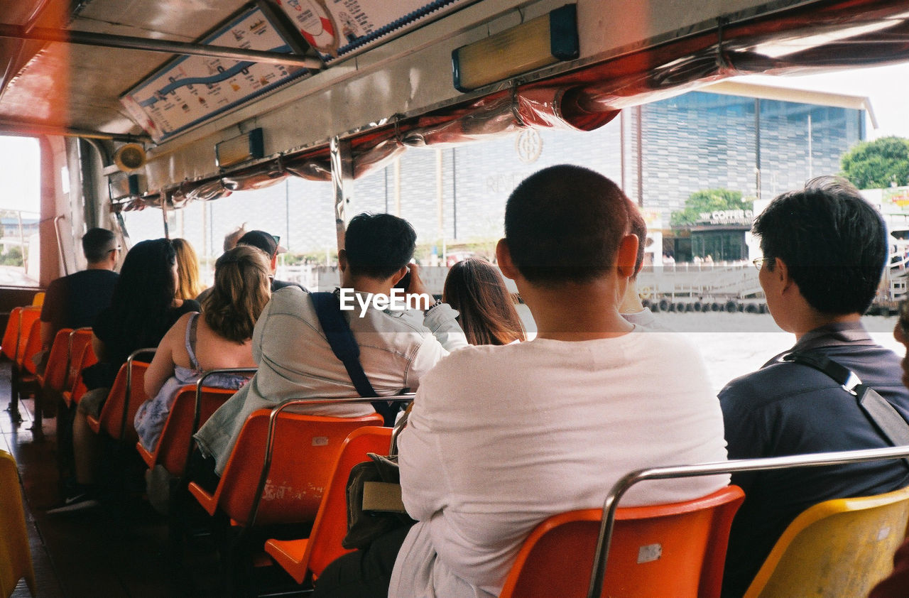 Rear view of people sitting in nautical vessel