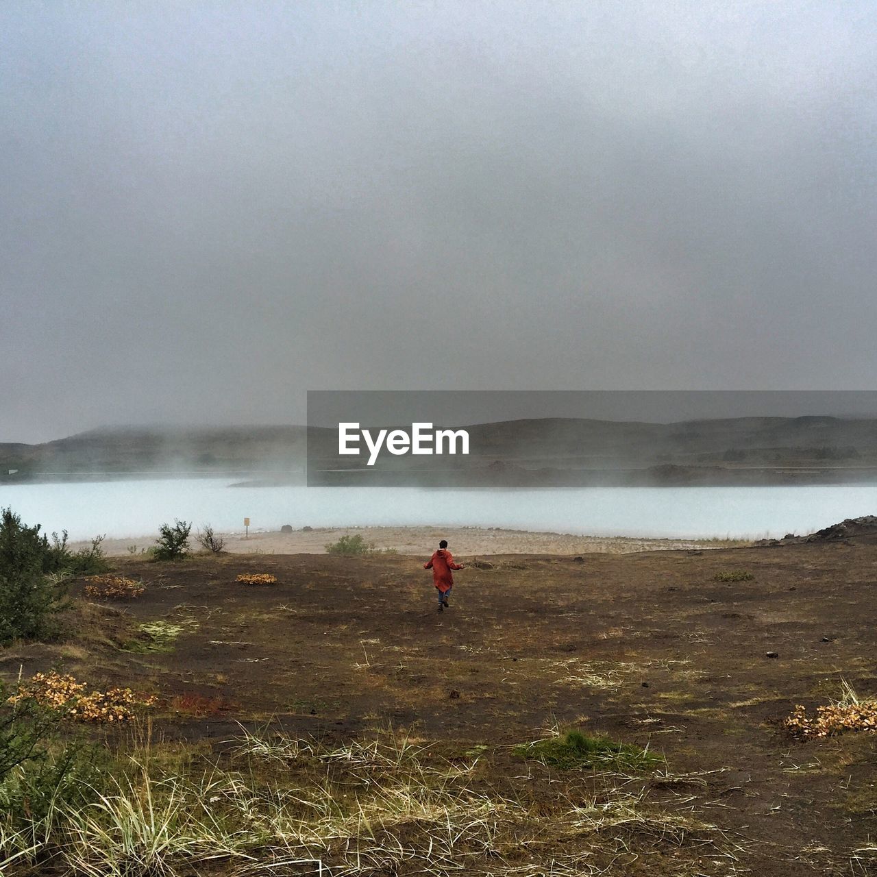 Rear view of female hiker on field against sky in foggy weather